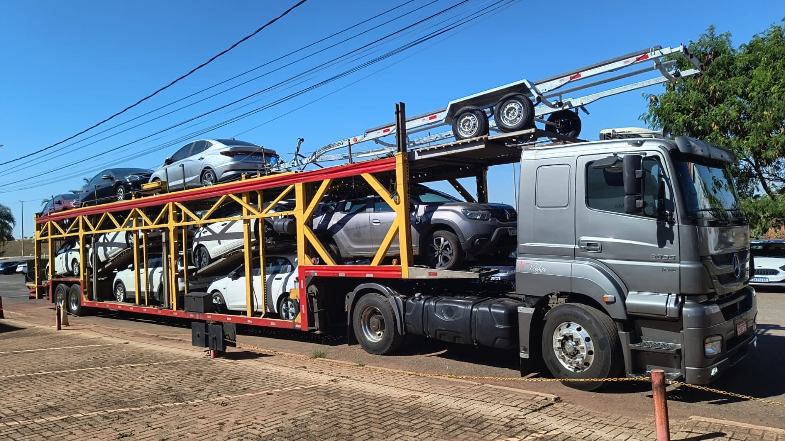 Cegonha Mercedes-Benz carregada com vários carros sob céu azul